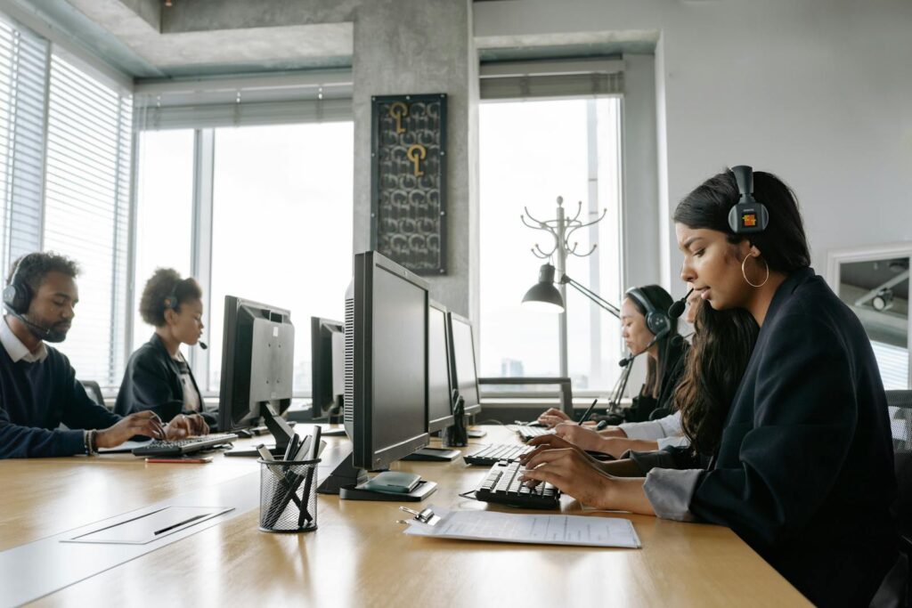 A team of call center agents working in a modern office with headsets and computers.